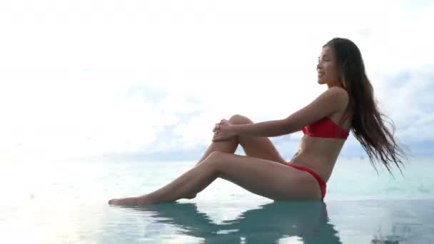 Lüks seyahat eden kadın tatil köyünde güneşleniyor, yaz tatillerinde havuzda güneşleniyor. Otelde uzanan bronz tenli seksi bikinili bayan.. — Stok video
