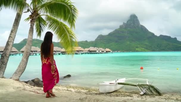 Бора Бора Отдых Путешественница женщина ходить по райскому пляжу Motu на французской Полинезии с горой Otemanu на традиционных каноэ outrigger ваа. Дама на роскошном отдыхе в надводном батискафе курортного отеля — стоковое видео