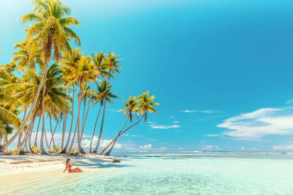 プライベートビーチアイランドのモツで美しい女性とビキニで完璧な象徴的なビーチを旅行休暇フランス領ポリネシア旅行で日光浴中に青いカクテルを飲みながらリラックスしてください。クルーズ船の目的地 — ストック写真