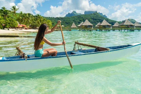 Francouzská Polynésie Tahiti cestovní dovolená koncept. Outrigger Kanoe polynéské vodní sportu žena pádlování v tradiční vaa loď. Vodní volný čas, Bora Bora nad vodou bungalov resort hotel — Stock fotografie