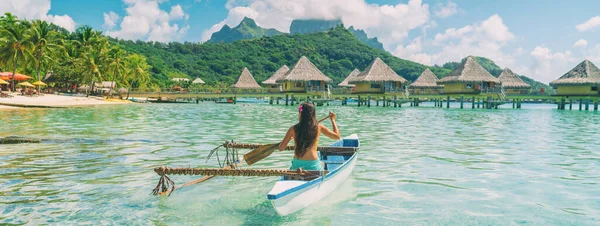 Bora Bora viaggi vacanza foto iconica. Outrigger Canoe - donna che remava nella tradizionale canoa polinesiana Outrigger francese. Monte Otemanu e bungalow sull'acqua resort hotel sport lifestyle — Foto Stock