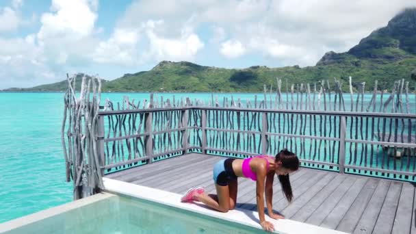 Kneeling leg lift butt toning Donkey Kick exercise - Asian fitness woman working out bodyweight exercises on Bora Bora travel vacation. Strength training her glutes with rear raised legs exercises — Stockvideo