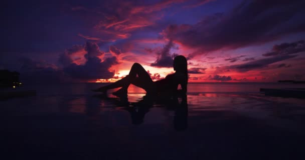 Paraíso atardecer idílica silueta de mujer de vacaciones nadando en la piscina infinita mirando los reflejos del cielo sobre el sueño del océano. Perfecto destino de viaje increíble — Vídeos de Stock