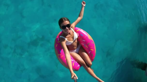 휴일 여행 재미있다. 바다에 떠 있는 도넛을 하고 셀카 스틱으로 완벽 한 물에 떠 있는 여자 가 바다 위를 떠다니는 도넛 위에 떠 있는. — 비디오