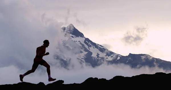 Hombre corriendo atleta silueta sendero corriendo en montaña cumbre fondo — Foto de Stock