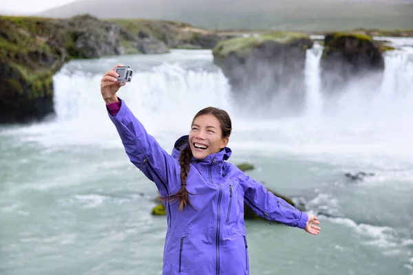 İzlandalı turist, Godafoss Şelalesi 'nde akıllı telefonuyla selfie çekiyor. — Stok fotoğraf