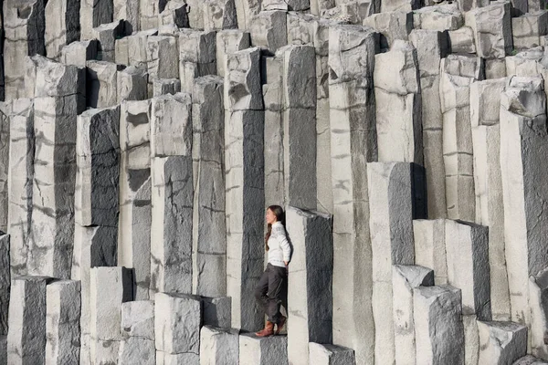 Islandia turista en la playa sentado en columnas de basalto Reynisfjara playa de arena negra — Foto de Stock