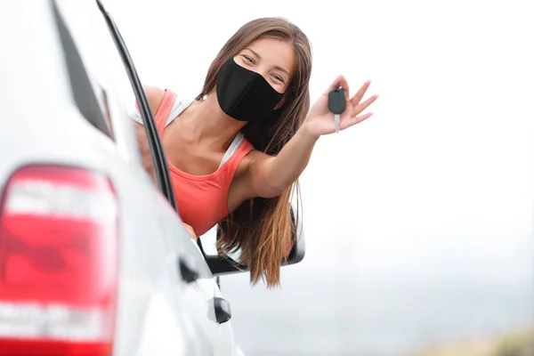 Conducción de coche nuevo mujer conductor feliz con máscara facial para coronavirus que muestra las llaves. Licencia de conducir escuela prueba éxito chica asiática coche propietario —  Fotos de Stock