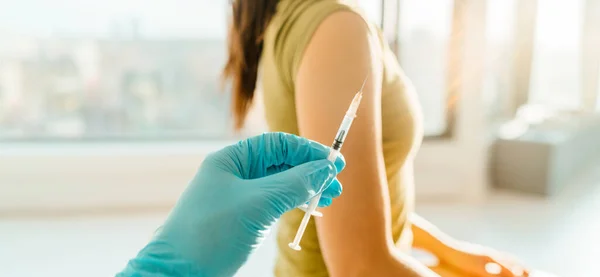 Vaccin tegen het coronavirus bij de medische kliniek banner. Vrouw die wordt gevaccineerd met een injectiespuit die wordt vastgehouden door een arts of verpleegkundige in de gezondheidszorg — Stockfoto