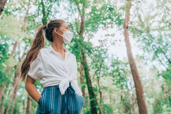 Wandelen in de natuur bossen met gezichtsmasker tijdens een coronavirus pandemie. Aziatische vrouw in duurzame eco-vriendelijke kleding modestof. Duurzaamheidsconcept voor mensen — Stockfoto