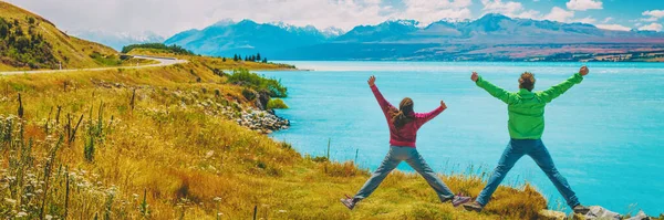 Happy podekscytowany para skoki radości na Nowej Zelandii Adventure Travel Vacation Concept. Ludzie w krajobrazie natury South Island, przez Aoraki aka Mount Cook. Sztandar panoramiczny — Zdjęcie stockowe