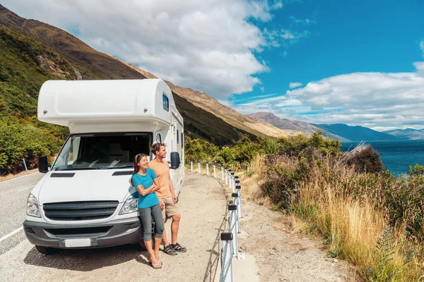 Motorhome lakókocsi kirándulás Új-Zélandon. Egy fiatal pár nyaralni megy. Két turista, akik a Pukaki-tóra és a hegyekre néznek, élvezhetik a kilátást és pihenhetnek a bérelt autó mellett — Stock Fotó