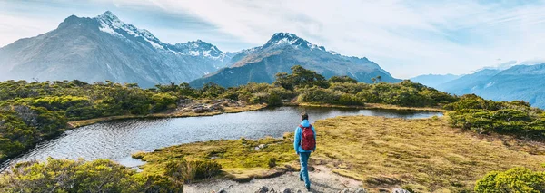 Wędrówki po Nowej Zelandii. Młody turysta spacerujący szlakiem po torze Routeburn w słoneczny dzień. Turysta depczący Key Summit Track w Parku Narodowym Fiordland w Nowej Zelandii. Sztandar panoramiczny — Zdjęcie stockowe