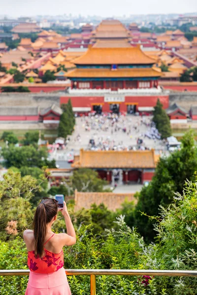 Κίνα καλοκαιρινά ταξίδια. Γυναίκα τουρίστας λήψη φωτογραφιών με κινητό τηλέφωνο εναέρια άποψη των αυτοκρατορικών παλατιών, παλιά ναούς, η απαγορευμένη πόλη στο Πεκίνο, Κίνα. Πάρκο Jingshan Gongyuan — Φωτογραφία Αρχείου