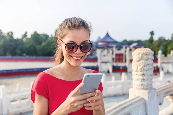 Turista asiático usando aplicativo de telefone para encontrar direções e guia durante a viagem em Pequim, China. Mulher chinesa feliz mensagens de texto no smartphone sms móvel — Fotografia de Stock