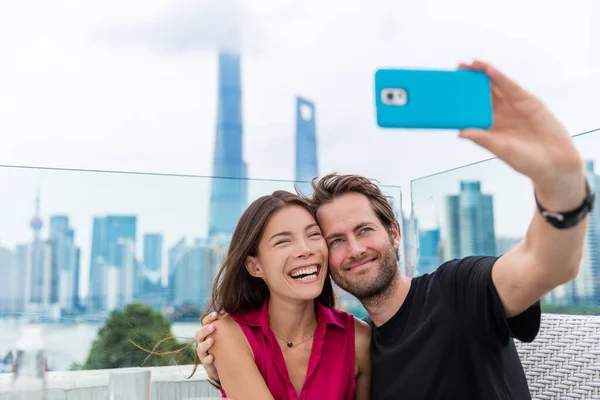 这对快乐的夫妇在上海自费旅行。不同种族的年轻人，中国妇女和白人男子在中国节日期间通过电话自画像，观看外滩和浦东 — 图库照片