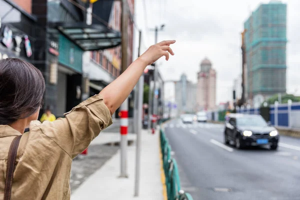 Een vrouw roept een auto aan op Shanghai Street. — Stockfoto