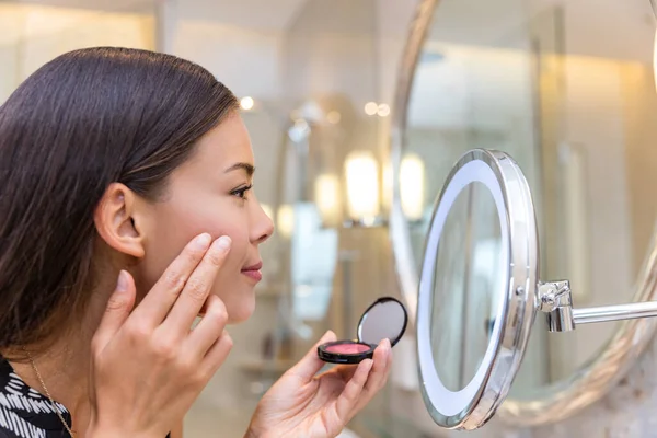 Asiatico donna putting blush looking in makeup mirror — Foto Stock