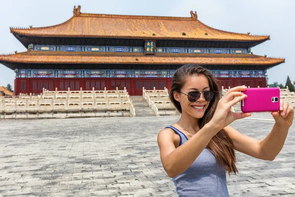 Feliz turista tomando fotos de teléfonos inteligentes en los viajes de Asia durante el verano en China. Mujer joven con gafas de sol haciendo fotos selfies con teléfono móvil — Foto de Stock