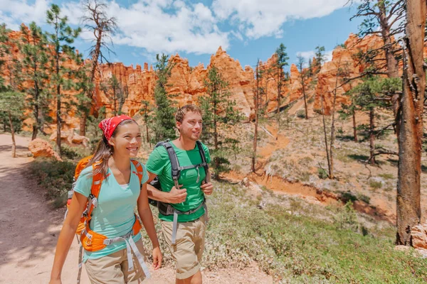 Hiking couple hikers walking smiling happy in summer mountain nature. Interracial couple Asian woman and Caucasian man in Bryce Canyon National Park landscape, Utah, United States — Φωτογραφία Αρχείου