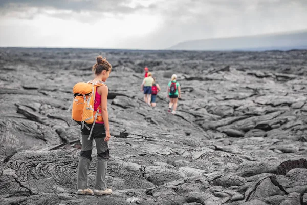 Hiking group of hikers walking on Hawaii volcano lava field hike adventure happy woman with backpack in Big Island, Hawaii. Tourists walking on guided tour trail outdoor USA summer travel vacation — Zdjęcie stockowe