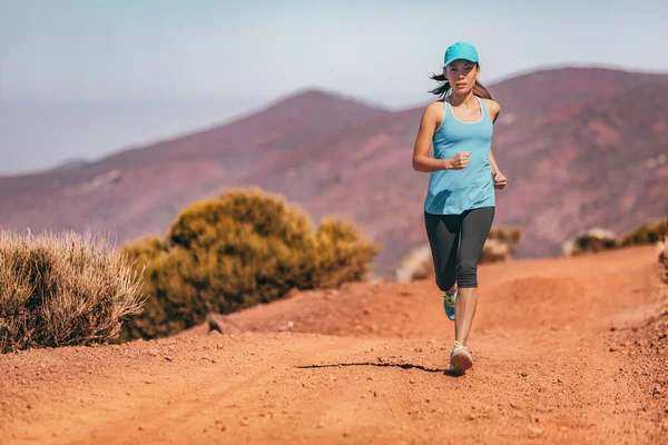 Running sports athlete woman trail runner wearing cap shoes leggings exercising in summer heat. Outdoor fitness active healthy lifestyle Asian girl training in desert mountain landscape —  Fotos de Stock