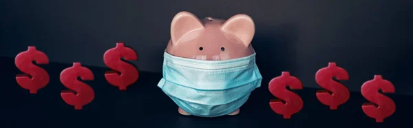 Kostenersparnis während des Konzepts einer Coronavirus-Pandemie. Sparschwein mit Gesichtsmaske und Banner mit roten Dollarscheinen. — Stockfoto