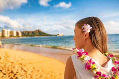 Hawaii woman wearing lei flower necklace and hair accessory on beach sunset for luau party or honeymoon wedding in Waikiki beach, Honolulu, holiday travel. clipart