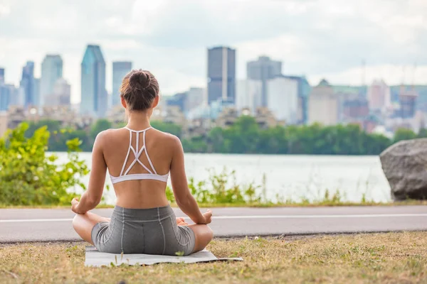 Zen jogi klasy na zewnątrz w parku miejskim kobieta wellness medytacji w lotosu stanowią outdoor na macie i trawie. Dziewczyna z tyłu siedzi — Zdjęcie stockowe