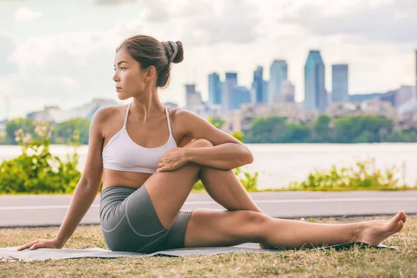 Yoga esneme egzersizi, parktaki açık hava fitness sınıfında omurga sağlığı için belini geren Asyalı kadına uyuyor. Omurga bükülmesi — Stok fotoğraf