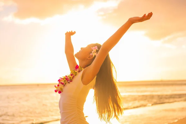 Mujer bailarina de hula de Hawái con collar de flores lei en la playa del atardecer bailando con los brazos abiertos libres al atardecer relajándose en vacaciones de viaje hawaianas. Chica asiática con flores frescas pelo, danza tradicional. —  Fotos de Stock