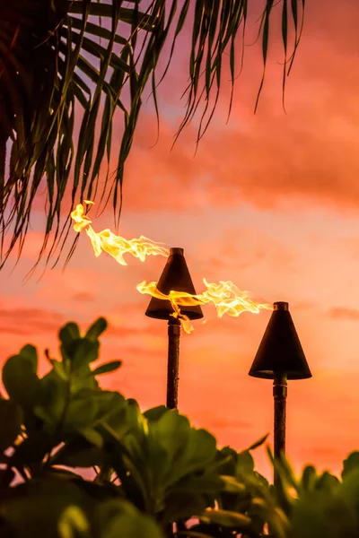 Hawaii luau party Maui fire tiki torches with flames burning against sunset sky clouds at night. Hawaiian culture travel background. — Stock Photo, Image