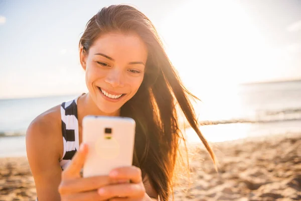 Smartphone ευτυχισμένη νεαρή γυναίκα που χρησιμοποιεί το κινητό τηλέφωνο στις καλοκαιρινές διακοπές παραλία διακοπές ταξίδια στη Χαβάη. Τουριστικός τρόπος ζωής Ασιατική κοπέλα χαμογελώντας λαμβάνοντας μια selfie με κινητό τηλέφωνο. — Φωτογραφία Αρχείου