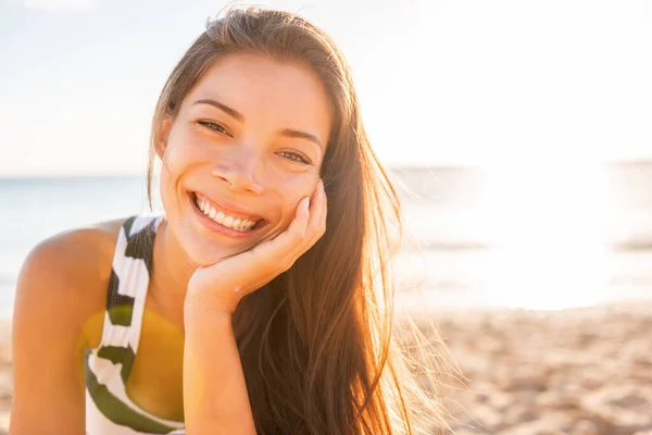 Mujer sonrisa feliz en la playa con la piel brillante saludable en la puesta del sol rayos de bengala fondo de verano. Asiática chica sonriendo confiado natural belleza. — Foto de Stock