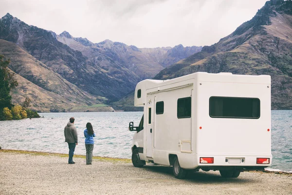 RV motorhome camper van road trip young people on New Zealand travel vacation adventure, Two tourists looking at lake and mountains on pit stop next to their rental car. — Stock Photo, Image