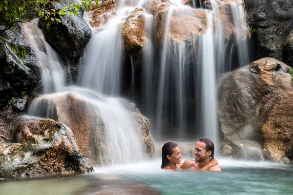 Pareja de vacaciones relajante en la naturaleza cascada. Escapada romántica destino viajes vacaciones personas felices juntos nadar bajo las caídas de agua natural —  Fotos de Stock