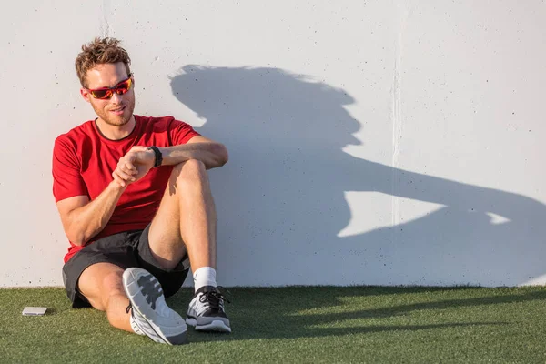 Smartwatch-Sportmann überprüft Fortschritte bei der intelligenten Fitness-Uhr nach dem Training. Sportler mit Sonnenbrille entspannt mit Online-App auf tragbarem Gerät. Outdoor Sommer aktiver Lebensstil — Stockfoto