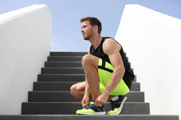Бігун, зв'язуючи бігові шнурки, готується до пробігу по тренажерних сходах, тренувавши тренування з кардіо по сходах. Старайтеся вести здоровий спосіб життя спортсмен, розвивати фітнес - мотивацію — стокове фото