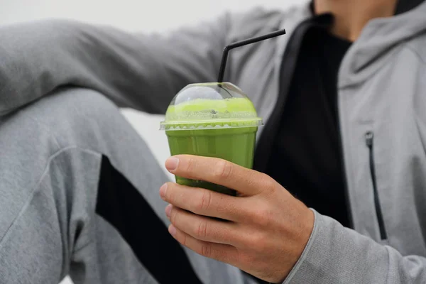 Zielony smoothie detox człowiek pije sok warzywny oczyścić. Sport sportowiec gospodarstwa plastikowe kubek śniadanie napój zbliżenie — Zdjęcie stockowe