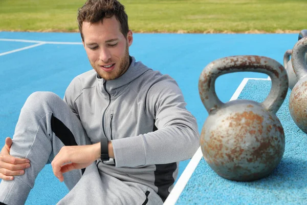 Fitness man kontrollera smartwatch under träning styrketräning på tyngdlyftning kettlebells utomhus gym. Hälsosam aktiv livsstil — Stockfoto