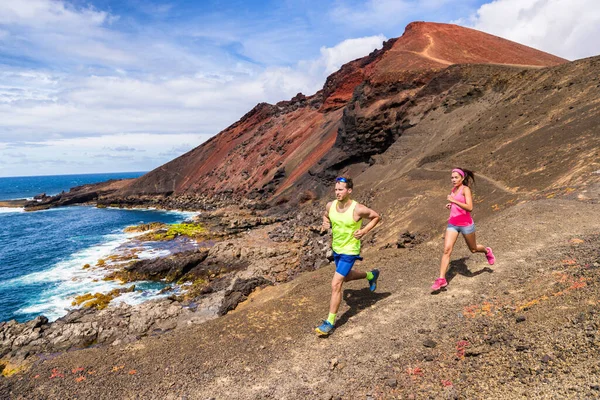 Trail running couple runners racing on mountain path in volcanic rocks nature landscape in summer outdoor. Ultra running race run — Stock Photo, Image