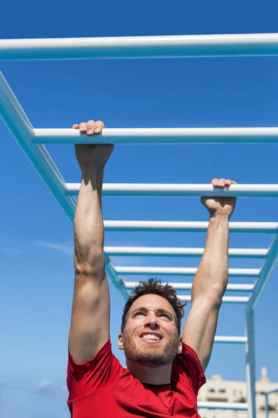 Fitness monkey bar uomo allenamento braccia muscoli sulla giungla palestra all'aperto in estate. Atleta che lavora fuori afferrando arrampicata sulle attrezzature della scala al centro di atletica sportiva — Foto Stock