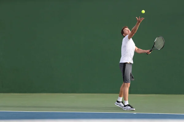 テニスは屋外の緑のコートで試合中にボールを提供する選手の男性にサービスを提供します。運動をするスポーツゲームのトレーニングをプレイ選手 — ストック写真