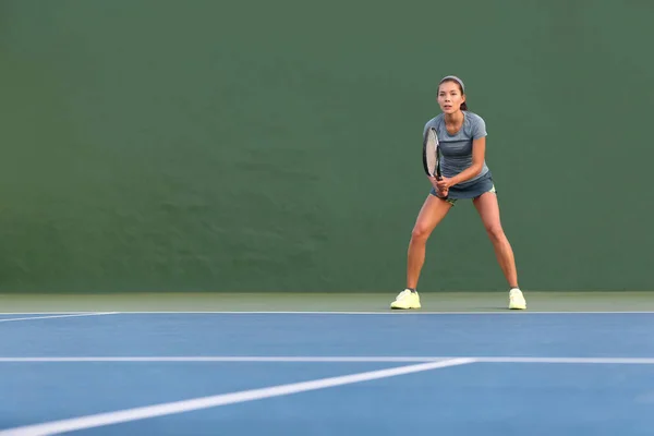 Jugadora de tenis mujer de pie lista para jugar esperando para recibir el servicio. Instructor de fitness al aire libre enfocado a jugar en pista dura sobre fondo verde — Foto de Stock