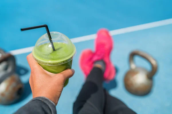 Fitness smoothie mujer pérdida de peso tomando selfie de alimentos de desintoxicación jugo verde con kettlebells en el gimnasio de entrenamiento al aire libre. Taza de plástico de mano de limpieza vegetal con pesas de kettlebell —  Fotos de Stock