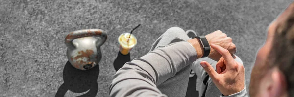Aplikacja fitness fit man za pomocą sportowego smartwatch na siłowni. Zamknięcie inteligentnego zegarka z kettlebell wagi i soku owocowego smoothie dla zdrowego aktywnego stylu życia miejskiego. Sztandar panoramiczny — Zdjęcie stockowe