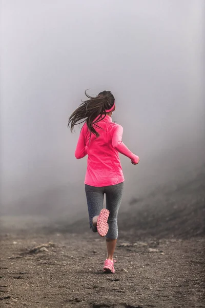 霧と雲の中の山の中でトレイルパス上で実行されているフィット女性ランナーを実行-ピンクのスポーツウェアで朝のジョギングトレーニング — ストック写真