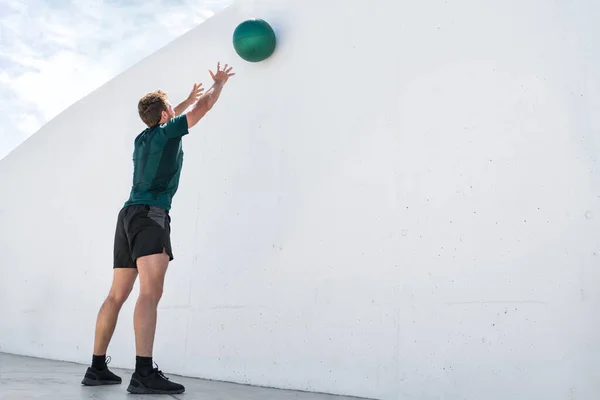 Fitness άνθρωπος ρίχνουν μπάλα ιατρικής στον τοίχο γυμναστήριο — Φωτογραφία Αρχείου