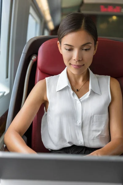 Jovem empresária chinesa trabalhando escrevendo e-mails no computador enquanto viaja para o trabalho pela manhã. Mulher comum sentada no banco da classe executiva em trem de alta velocidade. Viagens urbanas — Fotografia de Stock