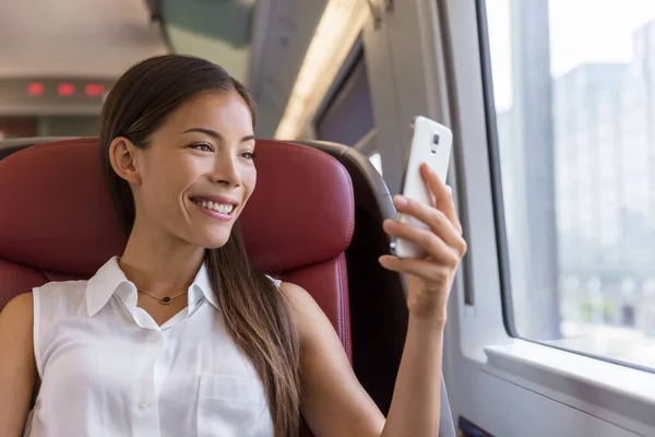 Asian woman using smartphone app taking pictures of the view while traveling in train. Happy young lady watching video holding mobile phone during transport on travel vacation — Stock Photo, Image